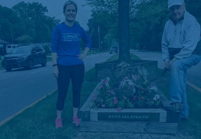 Man and woman standing next to flower garden with "Donate" centered on image in white